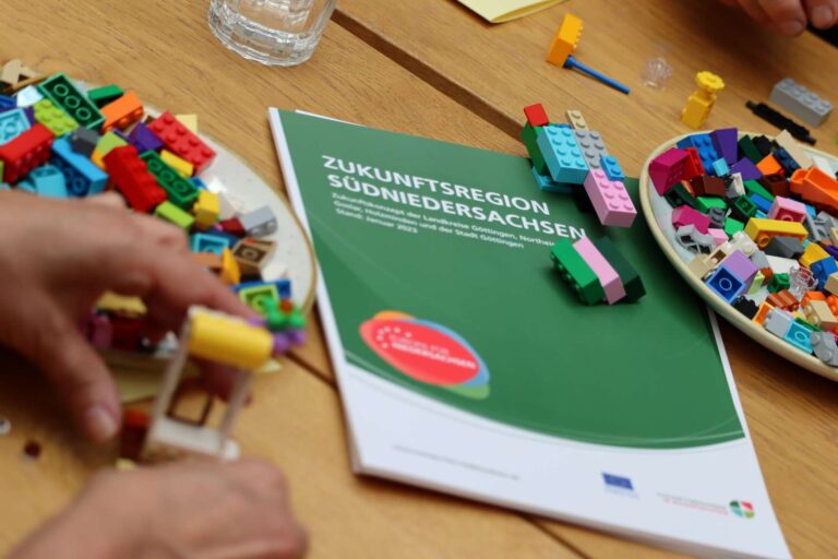 Zwischenbericht der Zukunftsregion Südniedersachsen auf einem Tisch, umgeben von bunten Bausteinen als Symbol für gemeinsame Projektentwicklung in der Region.