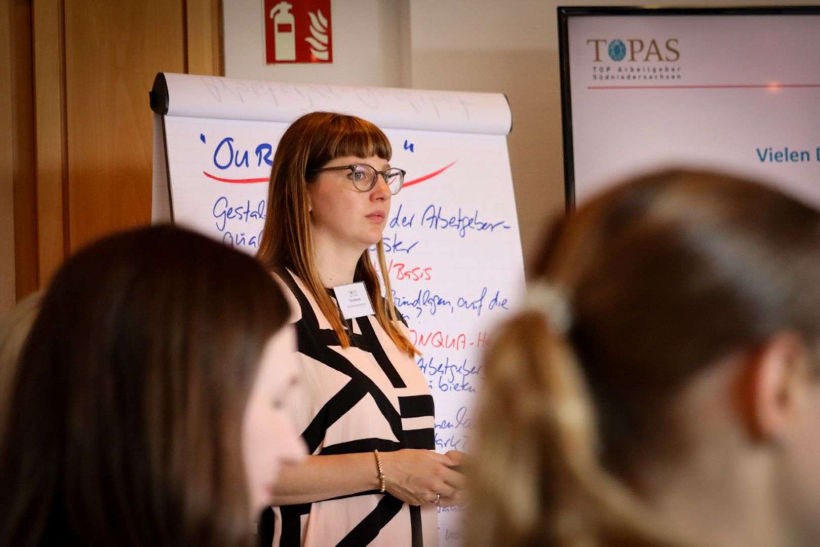 Eine Kursleiterin arbeitet mit den Teilnehmenden an einem Whiteboard. Titelbild für die Veranstaltung "TOPAS-Seminar: TOPAS Werkstatt – Euer Arbeitgeberwertversprechen schärfen".
