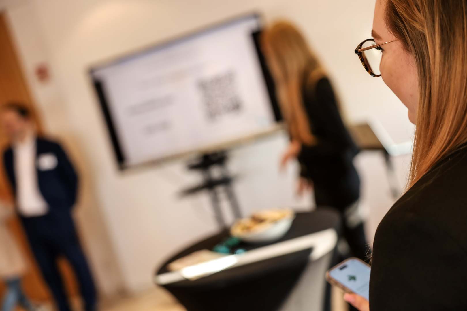 Person nutzt ein Smartphone während eines Online-Seminars. Im Hintergrund läuft eine Präsentation zu Social-Media-Strategien im Azubi-Recruiting. Bild der Veranstaltung: TOPAS-Webinar Azubi-Recruiting über Social Media – Strategien für die Generation Z und Alpha